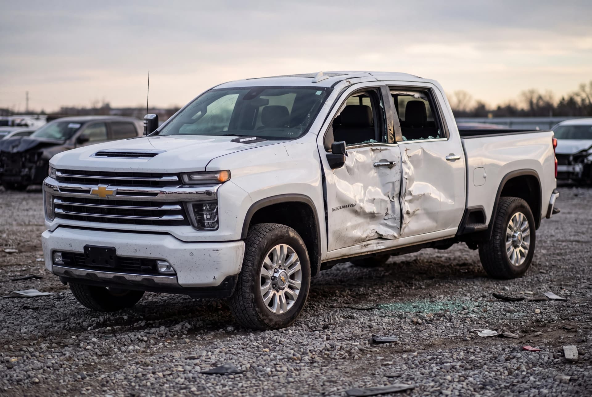A totaled Summit White 2023 Chevrolet Silverado 2500HD LTZ after a passenger-side collision