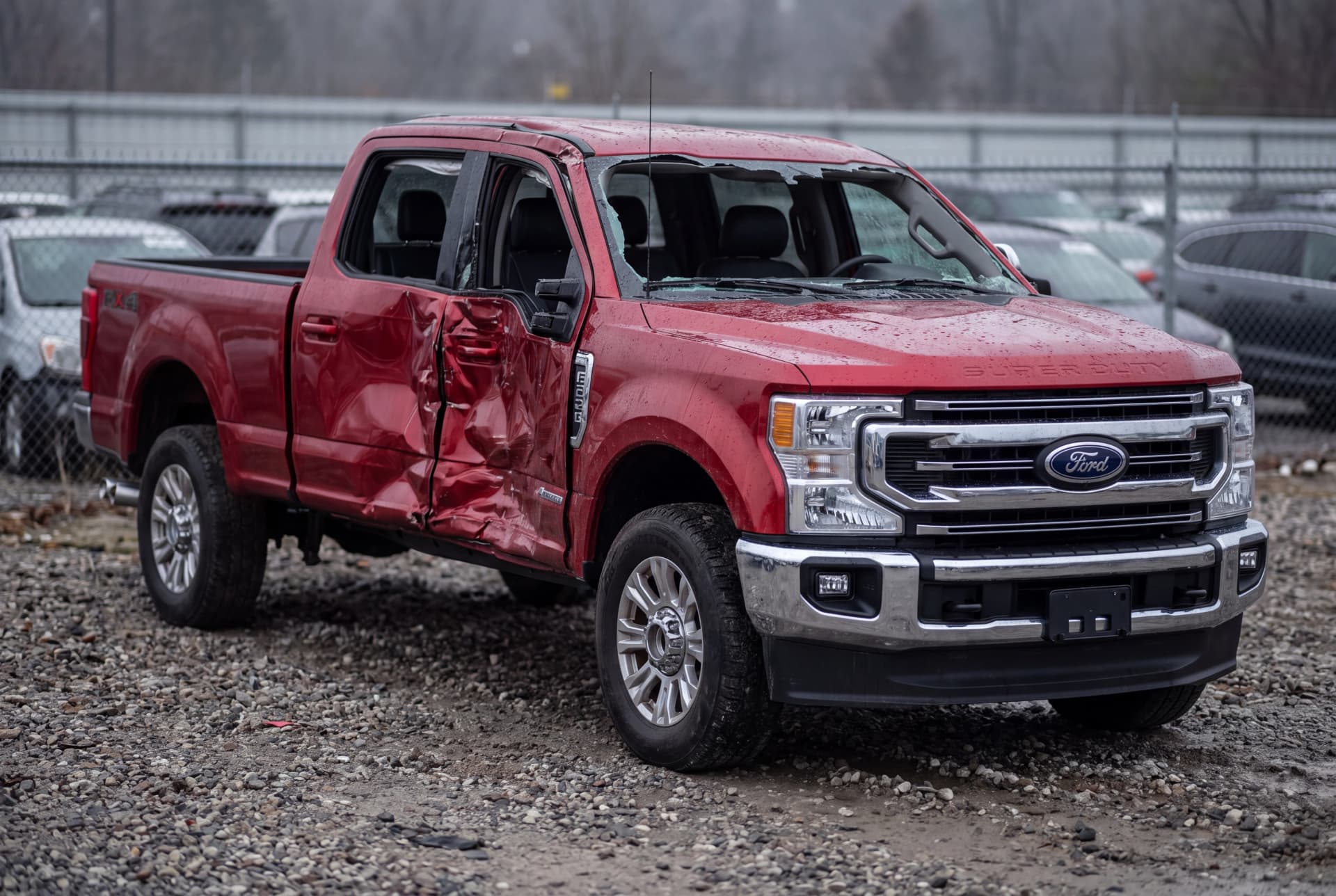 A totaled Rapid Red Metallic 2022 Ford F-250 Super Duty Lariat after a driver-side collision