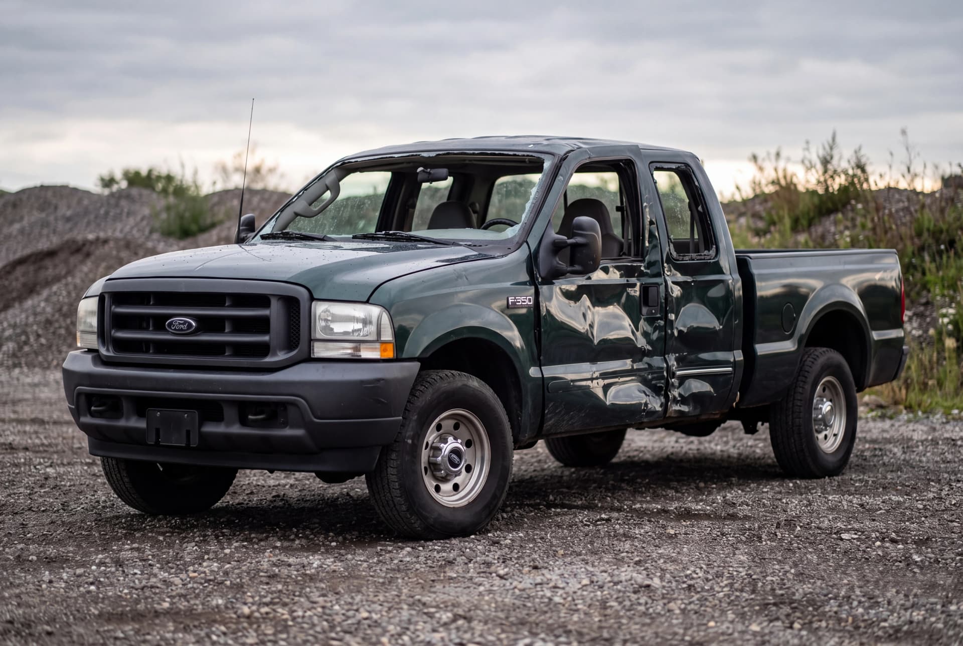 A totaled Dark Highland Green Metallic 2001 Ford F-350 Super Duty XL after a passenger-side collision