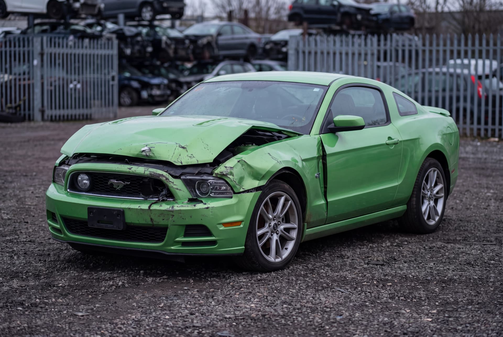 A totaled Gotta Have It Green Metallic 2013 Ford Mustang GT after a front-end collision